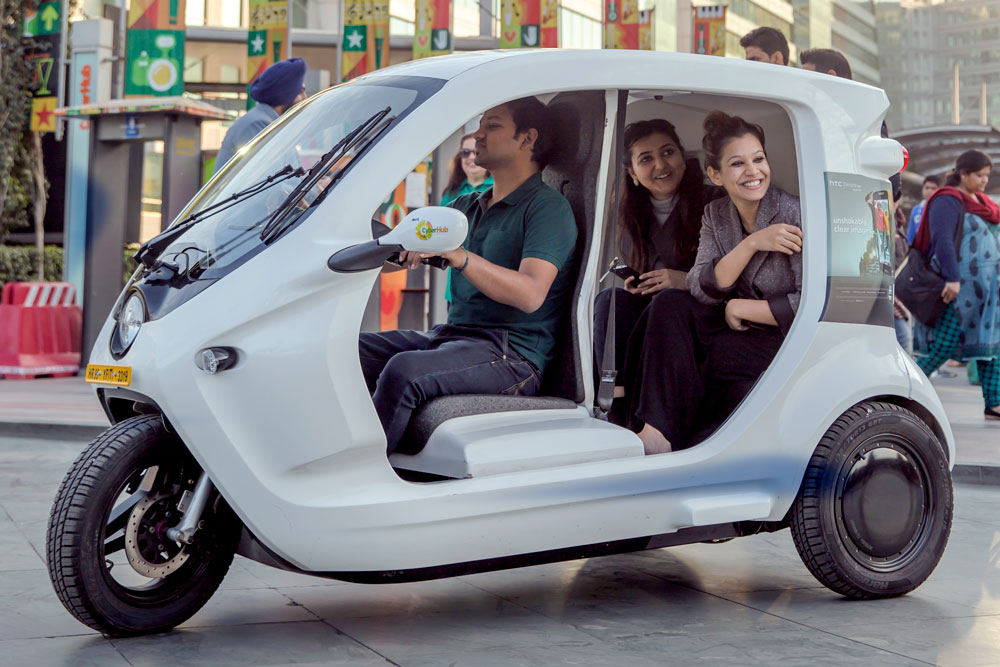 Three people riding in a small electric vehicle. Photo.