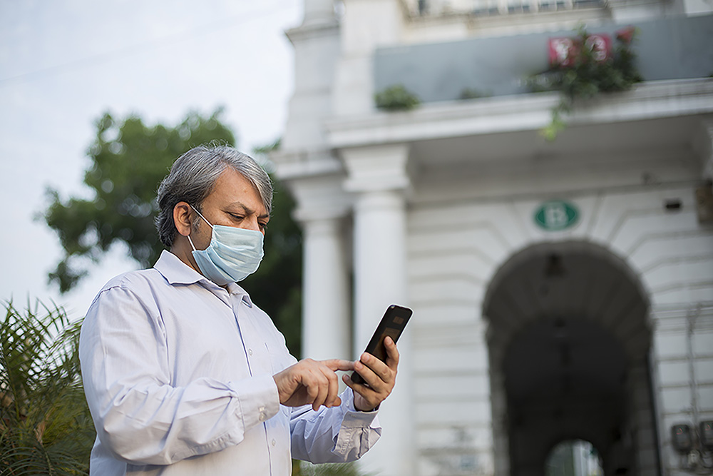 Indian man wearing face mask. looking at a cellphone. Photo.
