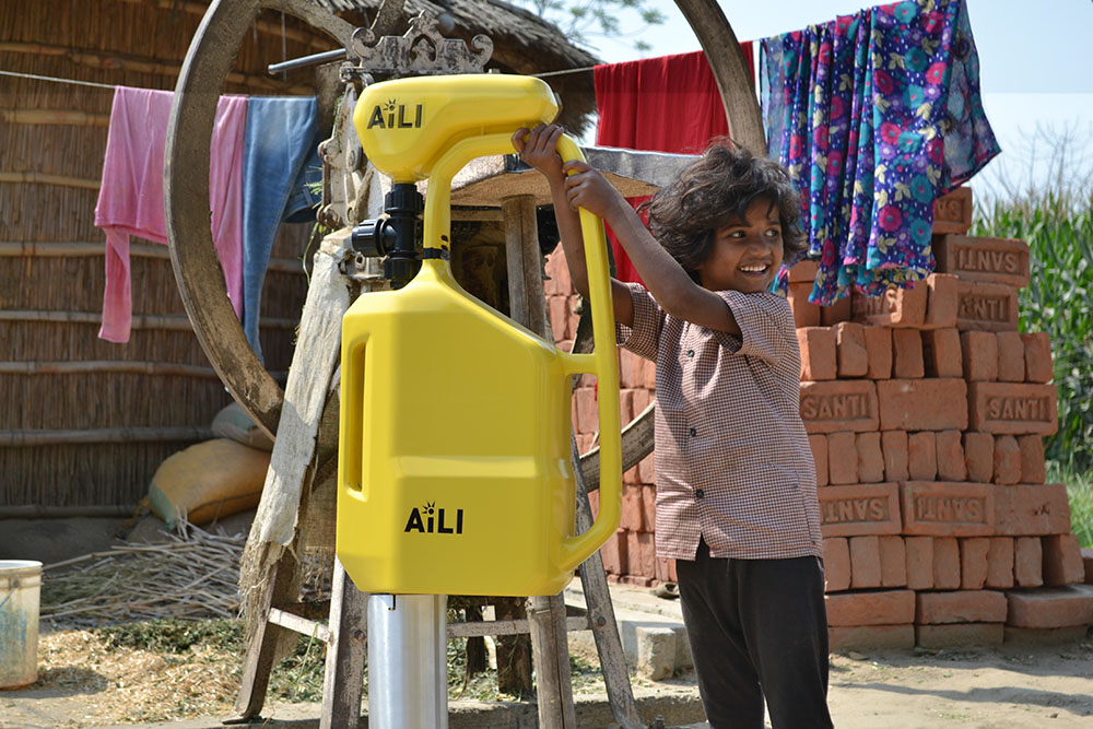 Indian child and yellow water pump. Photo.