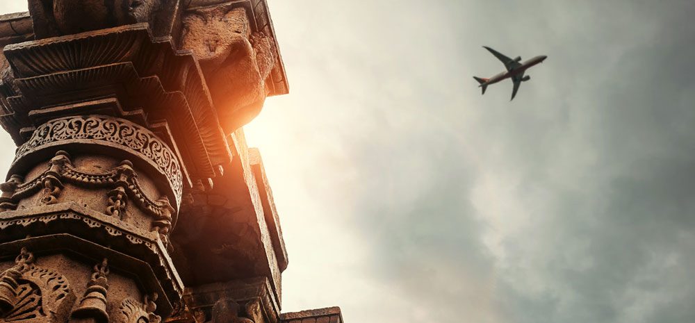 Airplane in the sky above ancient Indian building. Photo.