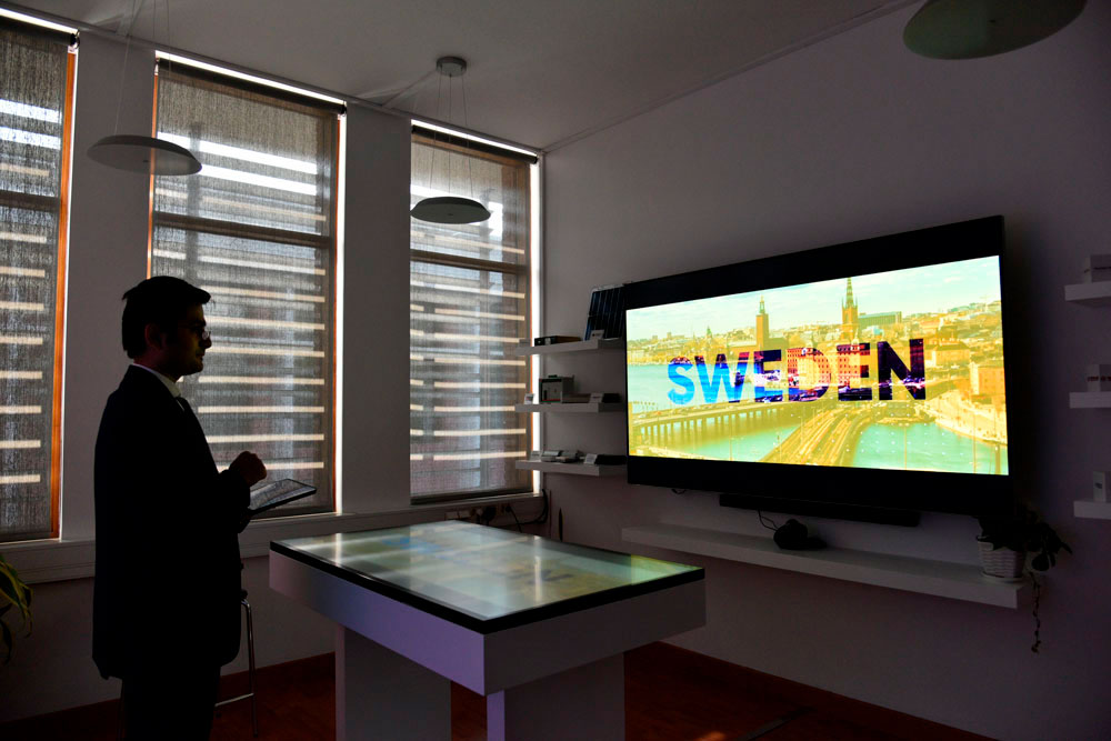 A standing man looking at a big screen. Photo.