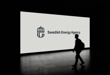 A person walking in front of a big screen with swedish energy agency's logotype on it.